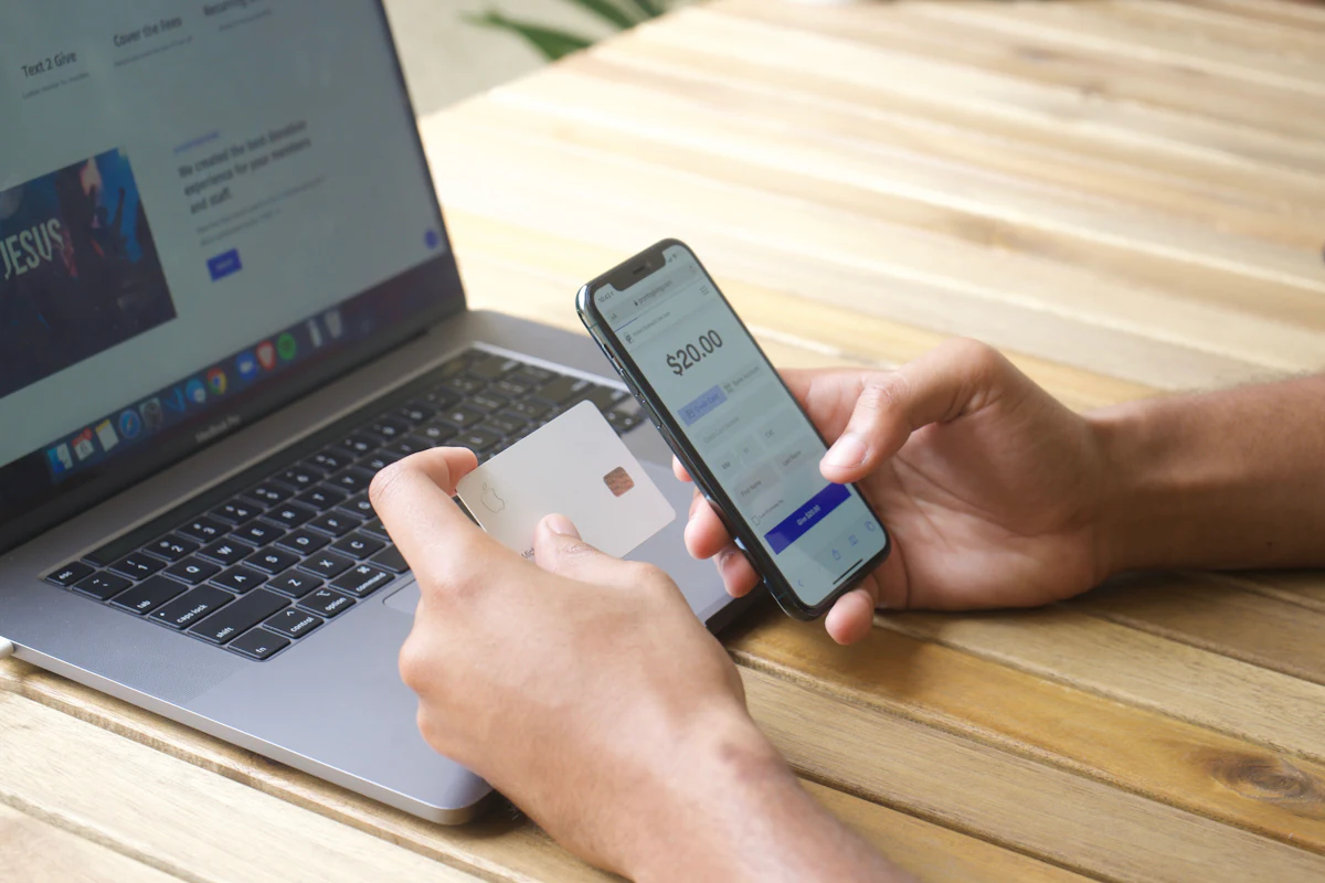Pago con tarjeta desde el celular frente a una laptop, comisiones por venta de una tienda online