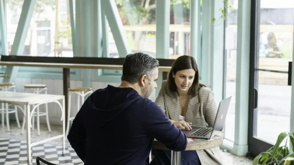 Dueña de negocio revisando su página web con un diseñador en una cafetería