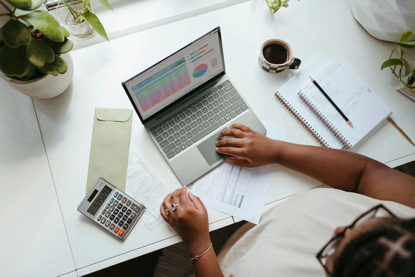 Dueña de negocio revisa sus cuentas con laptop y calculadora antes de vender por internet